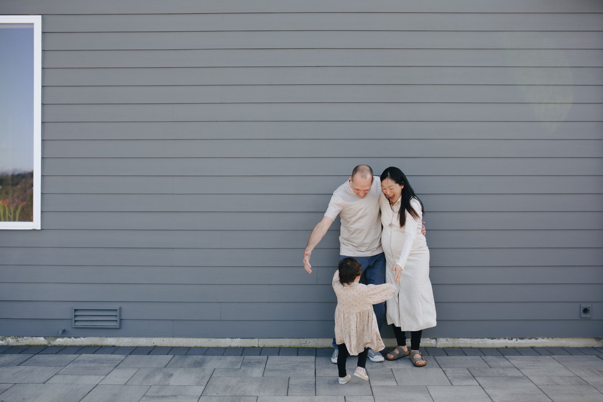 Happy Family Standing Beside A Gray Wall